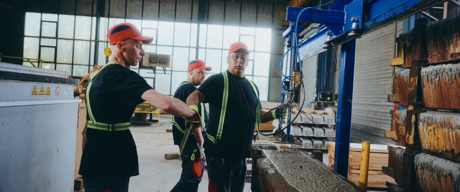 moll-rail-slowakia-drei-arbeiter-in-roten-kappen-bedienen-maschinen-an-betonform-in-fabrik moll-rail-slowakia-drei-arbeiter-in-roten-kappen-bedienen-maschinen-an-betonform-in-fabrik