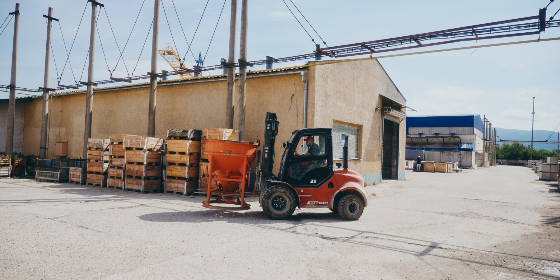 moll-rail-slowakia-red-forklift-carrying-orange-hopper-in-industrial-factory-yard