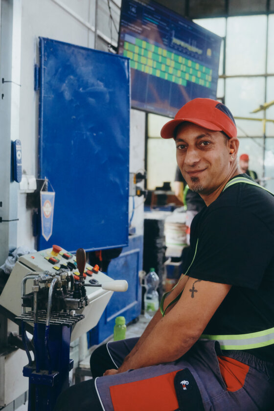 moll-rail-slowakia-smiling-worker-in-red-cap-sitting-at-control-panel-inside-factory moll-rail-slowakia-smiling-worker-in-red-cap-sitting-at-control-panel-inside-factory