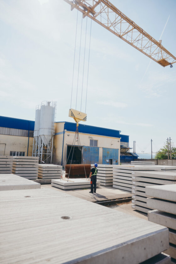 moll-rail-slowakia-worker-guiding-crane-lifting-concrete-panel-in-outdoor-storage-yard