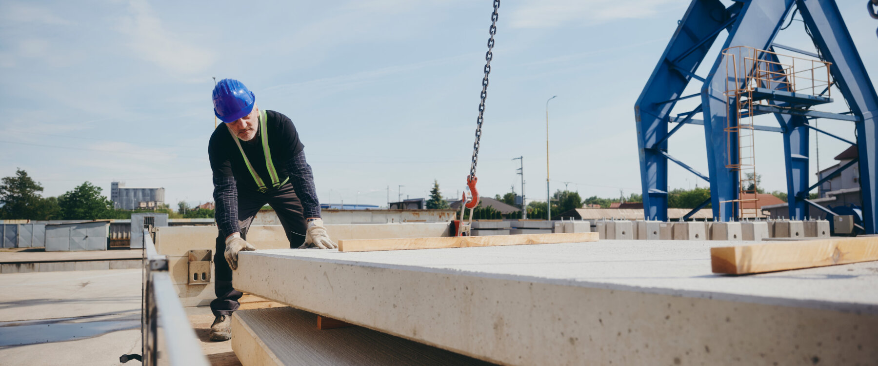 moll-rail-slowakia-worker-in-blue-hardhat-guiding-concrete-slab-with-crane-in-storage-yard moll-rail-slowakia-worker-in-blue-hardhat-guiding-concrete-slab-with-crane-in-storage-yard