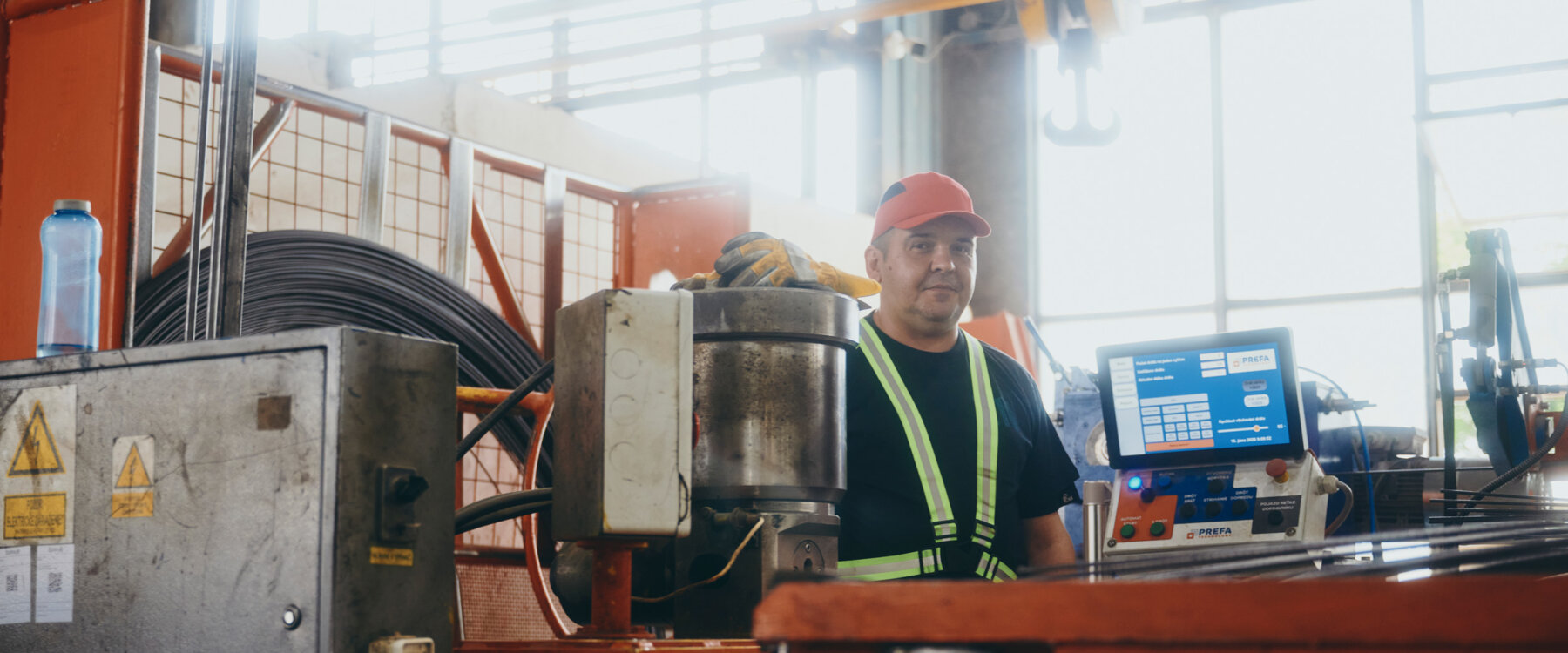 moll-rail-slowakia-worker-in-red-cap-standing-behind-machine-control-panel-in-factory moll-rail-slowakia-worker-in-red-cap-standing-behind-machine-control-panel-in-factory
