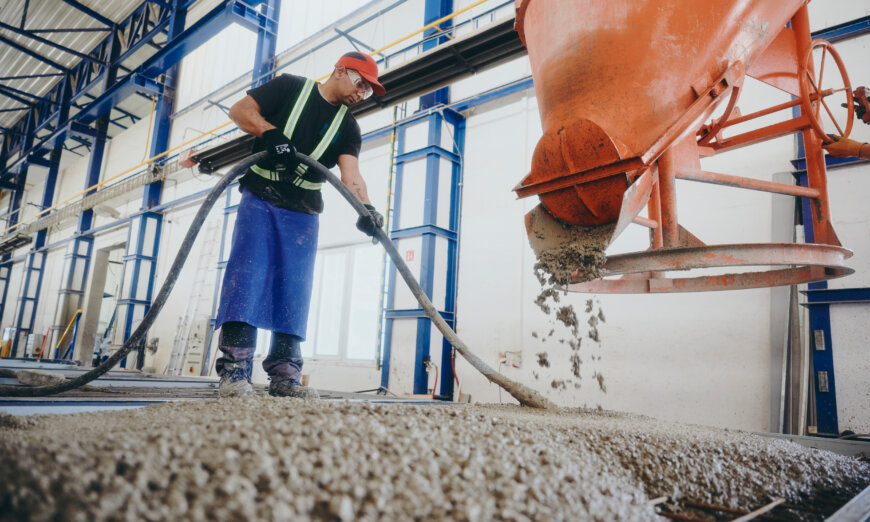 moll-rail-slowakia-worker-pouring-wet-concrete-from-orange-hopper-in-factory moll-rail-slowakia-worker-pouring-wet-concrete-from-orange-hopper-in-factory